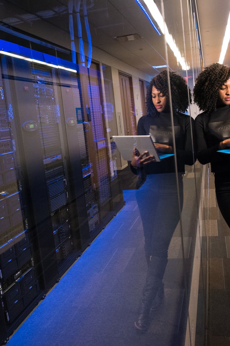 A woman using a laptop navigating a contemporary data center with mirrored servers.