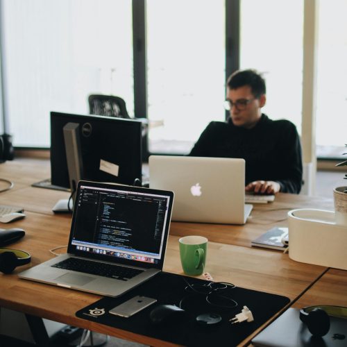 pexels-photo-2102416-2102416 A web developer working on code in a modern office setting with multiple devices.